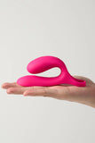 Pink Myvelvettouch Cock Ring and Remote Control Couple Vibrator held in a hand against a light gray background