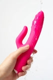 Pink Myvelvettouch G-spot Tapping and Clitoral Stimulation Vibrator held by a hand against a white background