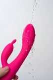 Pink Myvelvettouch Heated Rabbit Vibrator with water being sprayed on a white background