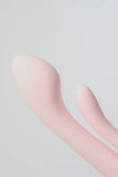 Close-up of a pink silicone Myvelvettouch Multifunctional Clitoral Stimulator Dual Head Vibrator on a light gray background