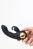 Black and gold Myvelvettouch Rabbit Clitoral Stimulator and Finger G-spot Vibrator Massager held by a hand on a white background