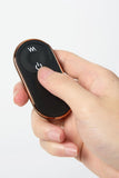 Hand holding a black remote control with copper accents of Myvelvettouch Rabbit Couple Vibrating Cock Ring on a white background