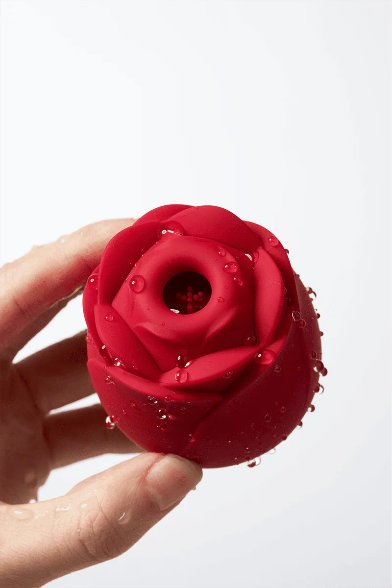 Myvelvettouch Rose Toy Clitoris Sucking and Slapping Massager held by a hand on a white background