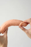 Two hands holding a large Myvelvettouch Suction Cup Vibrating Dildo with Thrusting and Remote Control against a light gray background