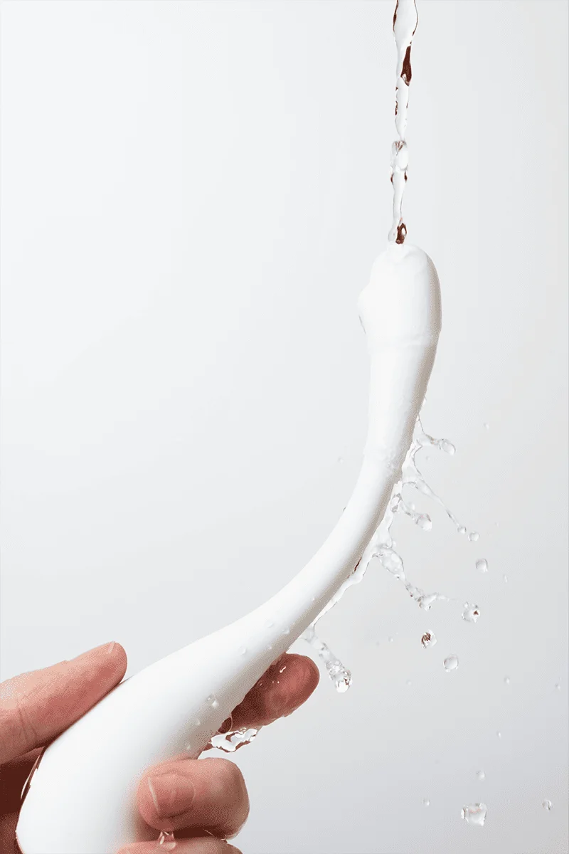 Myvelvettouch Swan Neck G-spot Stimulator Vibrator held by a hand with water splashes on a white background