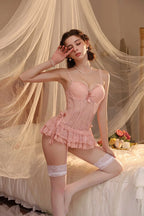 Woman in a pink lingerie set sitting on a bed with a soft, romantic atmosphere.