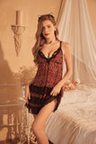 Woman in a leopard print Myvelvettouch nightgown sitting on a bed in a softly lit room.