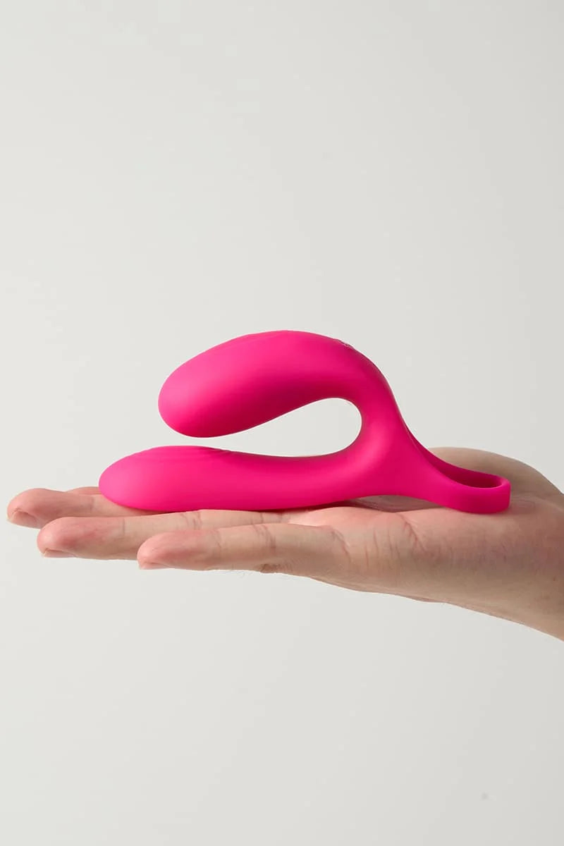 Pink Myvelvettouch Cock Ring and Remote Control Couple Vibrator held in a hand against a light gray background