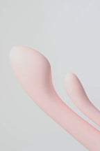 Close-up of a pink silicone Myvelvettouch Multifunctional Clitoral Stimulator Dual Head Vibrator on a light gray background