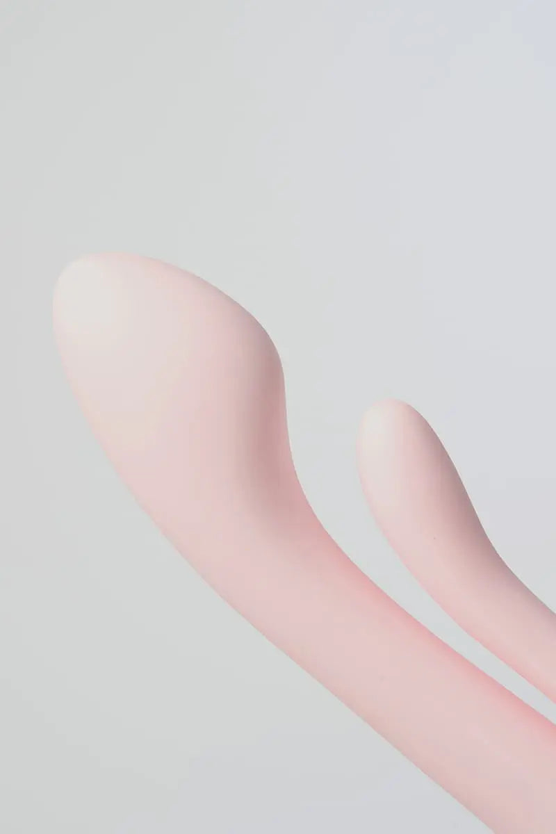 Close-up of a pink silicone Myvelvettouch Multifunctional Clitoral Stimulator Dual Head Vibrator on a light gray background
