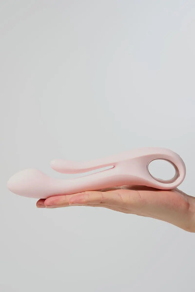 Pink Myvelvettouch Multifunctional Clitoral Stimulator Dual Head Vibrator held in a hand against a light gray background