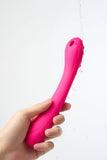 Pink Myvelvettouch Portable Clitoral Suction and Vibrator 2-in-1 held by a hand against a white background