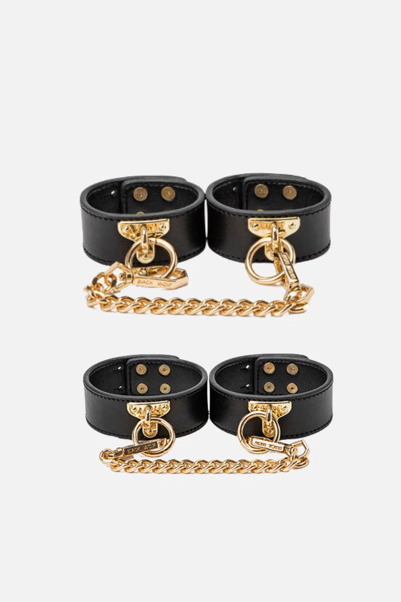 Black leather cuffs with gold chains on a white background